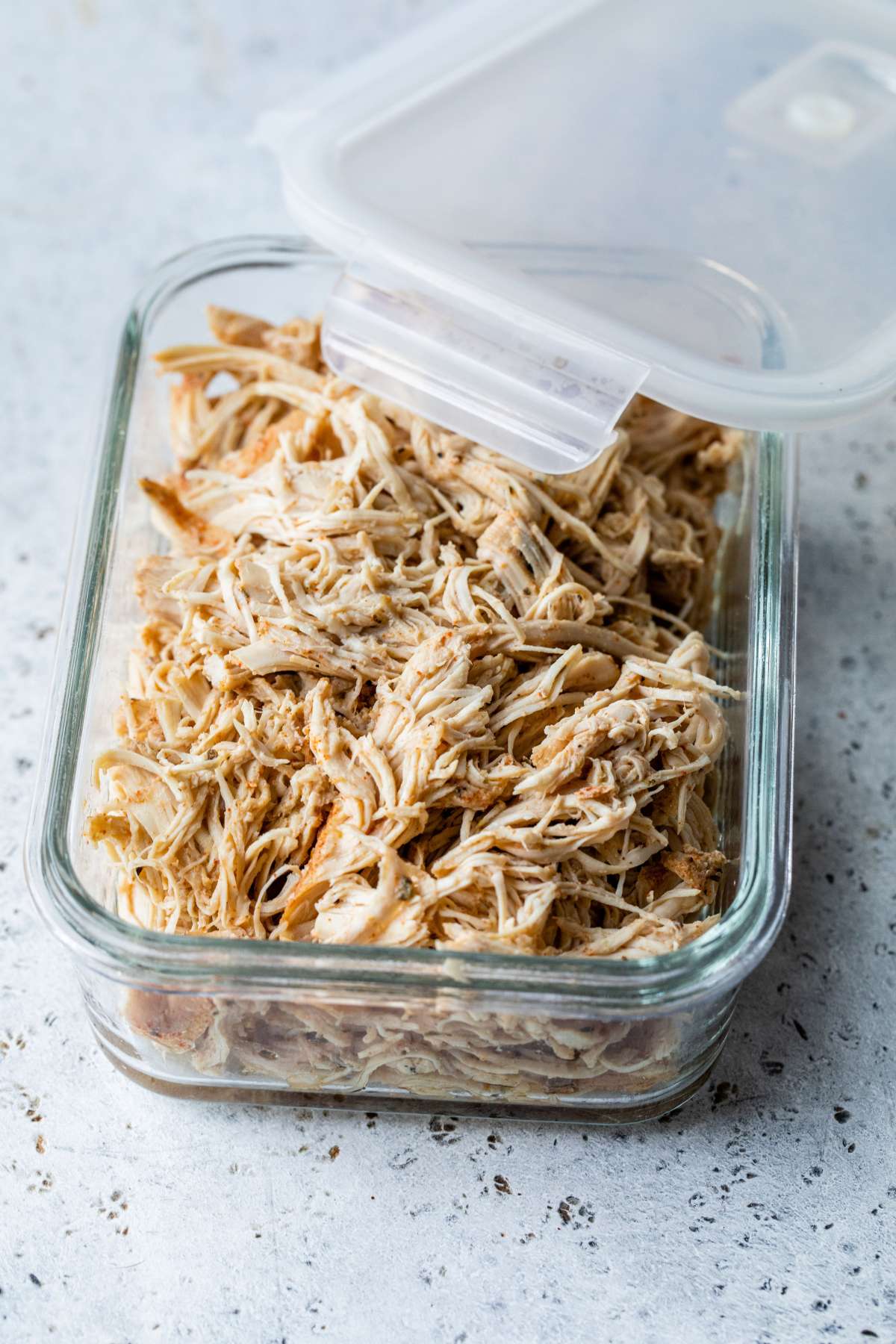 Shredded chicken in a glass storage container.