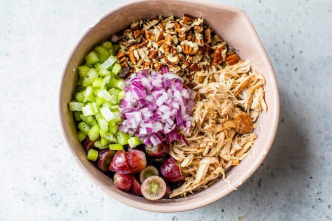 Pecans, chicken, red onion, grapes and celery in a large bowl.