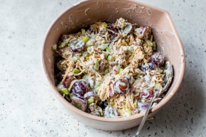 Stirring together chicken salad with Greek yogurt dressing in a large bowl.