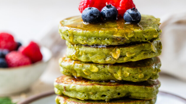 Stack of healthy spinach pancakes topped with oats and berries