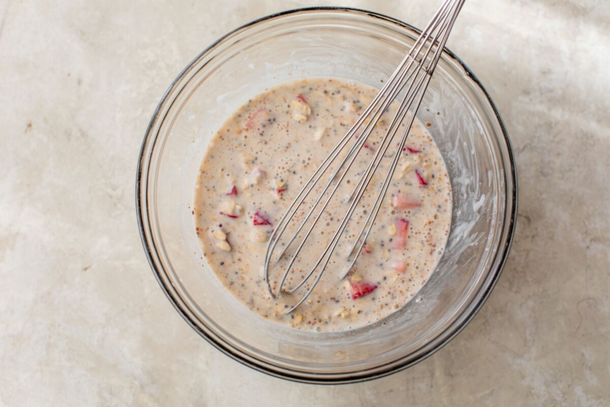 Whisking yogurt, milk, oats and strawberries in a bowl.