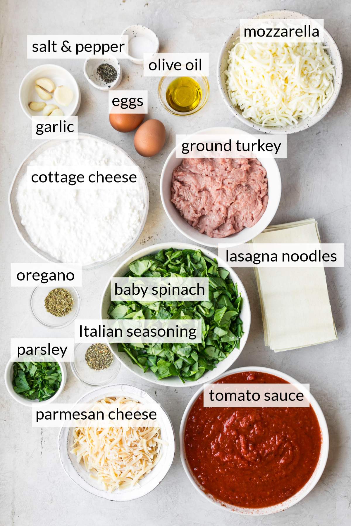 Small bowls with tomato sauce, ground turkey, cottage cheese, mozzarella, spinach and seasonings.