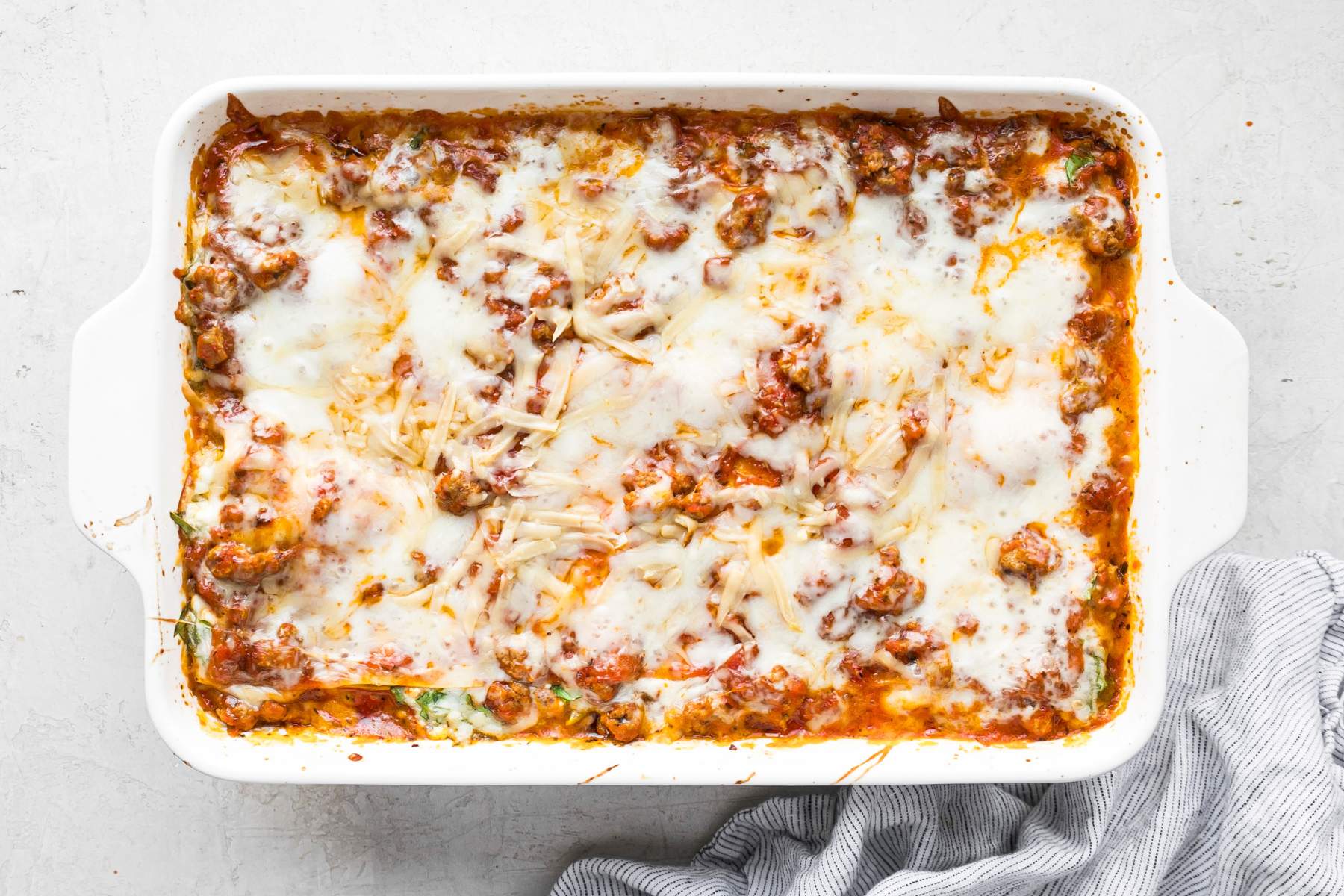 Baked lasagna in a white casserole dish.