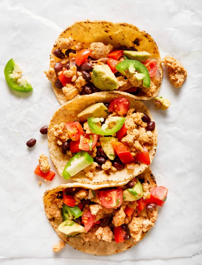 three turkey tacos with toppings on parchment paper