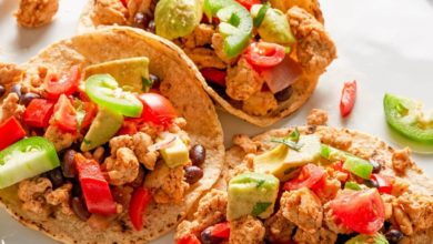 three tacos on a white plate served with lime wedges and jalapeรฑo slices